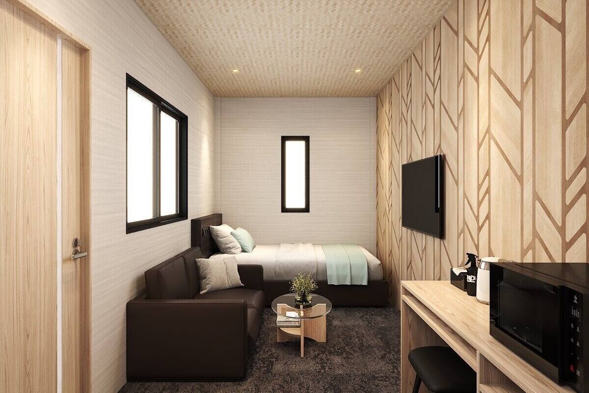 Una habitación moderna con cama, sofá, televisor y una mesita.