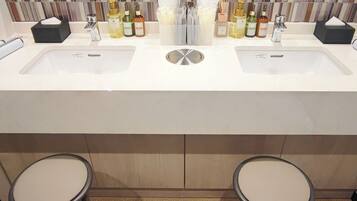 A bathroom with two sinks, a mirror, and two stools.