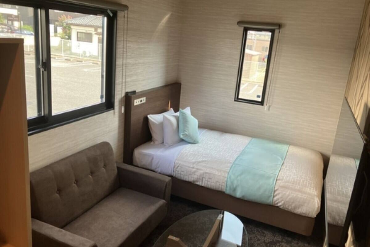 Una habitación compacta con cama, sofá y una mesita.