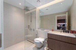 Ein modernes Badezimmer mit einer Duschkabine, einer Toilette, einem Waschtisch mit Spiegel und einem Waschbecken.