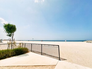 A beach with a clear sky, a sandy area, and a metal fence. - Contemporary La Mer 1BR w/ Beach Access (Dubai)