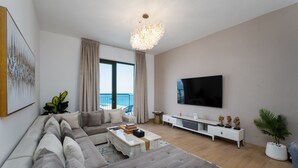 Una sala de estar moderna con un sofá grande, una mesa de centro, un televisor y vistas a un balcón.