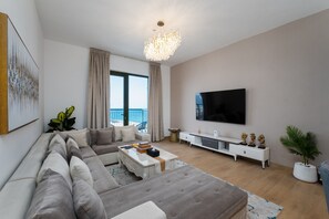 Un salon moderne avec un grand canapé, une table basse, un téléviseur et une vue sur le balcon.