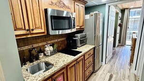 Una cocina con armarios de madera, un microondas de acero inoxidable, un lavaplatos y un refrigerador.