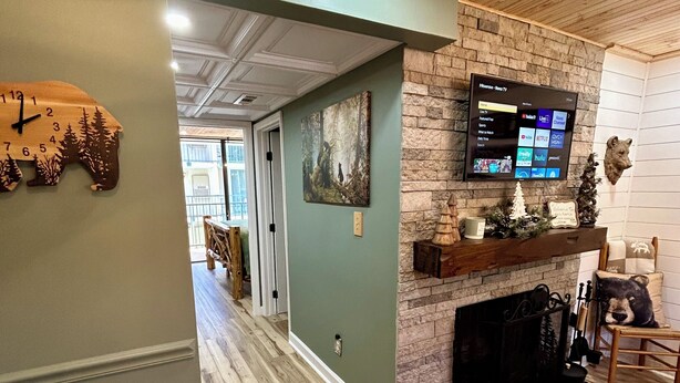 Un interior acogedor con chimenea, televisor montado y techo de madera.