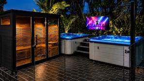 A spa area with wooden benches, a hot tub, and a television screen displaying a performance.