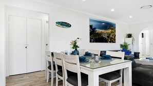 Un comedor con una mesa de vidrio, sillas de madera y una puerta blanca.