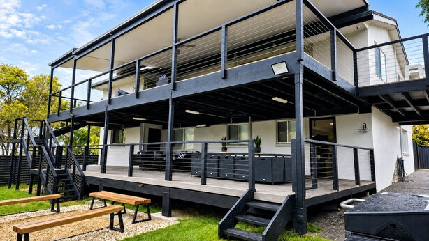 Un edificio moderno de varios pisos con terraza al aire libre, una escalera y un área cubierta.
