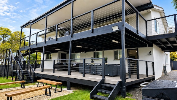 A modern multi-story building with outdoor seating, a staircase, and a covered area.