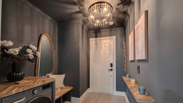 A hallway with a washing machine, a bench, a door, and a shelf with candles. - Magnolia Studio-Guest Unit (Houston)