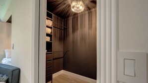 A walk-in closet with a dark wall, a chandelier, and a wooden floor. - Magnolia Studio-Guest Unit (Houston)