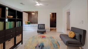 A modern living room with a sofa, a round rug, a bookshelf, and a ceiling fan. - Magnolia Studio-Guest Unit (Houston)