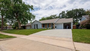 A residential house with a garage, a driveway, and a lawn. - Magnolia Studio-Guest Unit (Houston)