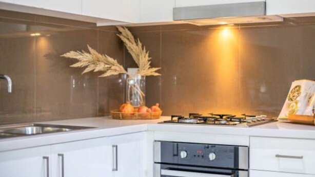 Une cuisine moderne avec des meubles blancs, une cuisinière à gaz et un four encastré.