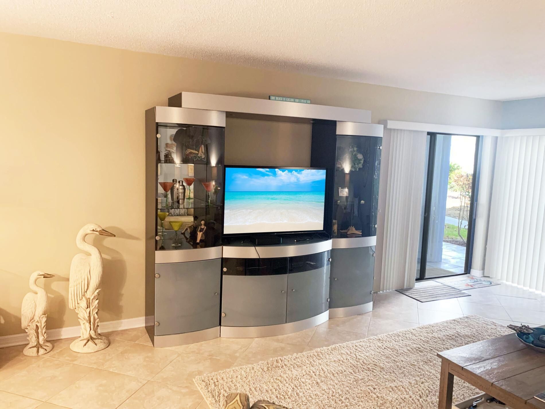 A modern living room with a curved entertainment unit, a flat-screen TV, and decorative items.