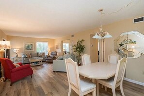 Relax in this stylish living room with a dining area, featuring a comfortable sofa, armchair, and dining table.