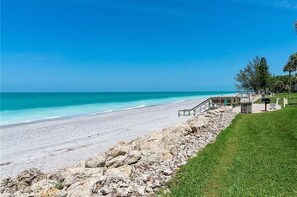 Enjoy ocean views from this beachfront property, featuring a paved walkway, seating area, and barbecue grill.
