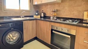 A modern kitchen with a washing machine, oven, and gas stove. - Marrakech Prestigia Piscine Golf Saphir (Marrakech)