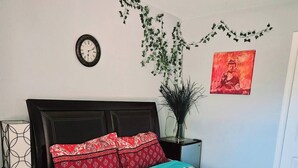 A bedroom with a bed, a wall clock, a potted plant, and a red artwork. - Charming 1-bedroom house in superb San Jose with AC, WiFi (San Jose)