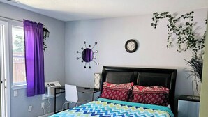 A bedroom with a bed, a desk, a chair, a clock, and a window with curtains. - Charming 1-bedroom house in superb San Jose with AC, WiFi (San Jose)