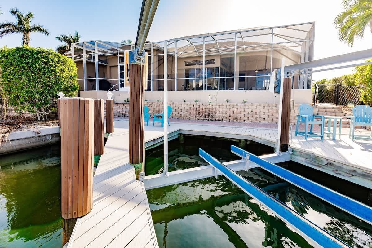 Una moderna casa flotante con cerramiento de vidrio, un muelle y una pequeña piscina.