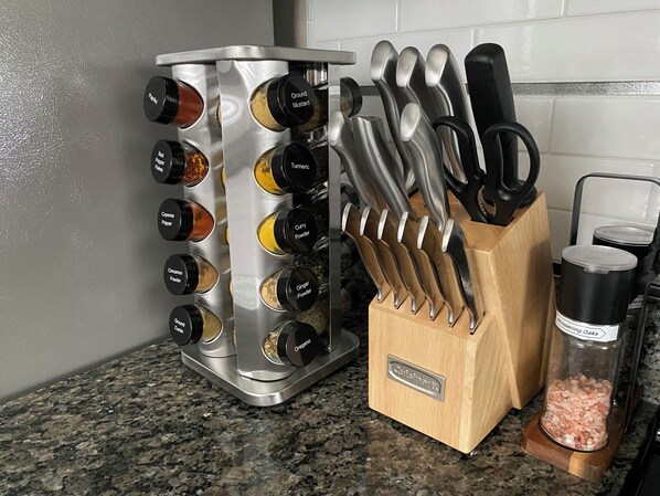 Una encimera de cocina con un especiero, un bloque de cuchillos y un recipiente con sal.