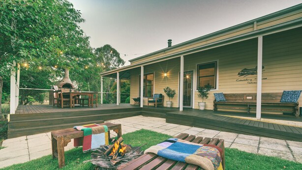 A covered outdoor patio with wooden furniture, a fire pit, and a brick oven. - Country House Retreat (Nungurner)