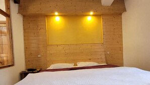 A bedroom with a wooden headboard, a bed with white bedding, a nightstand, and a ceiling fan. - Hills Homestay and Devallya (Manali)