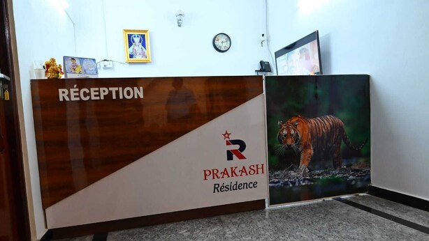A reception desk with a wooden finish and a sign reading "RÉCEPTION PRAKASH Résidence". - Prakash Residence (Puducherry)