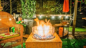 An outdoor patio with a fire feature, wicker furniture, and a grill.