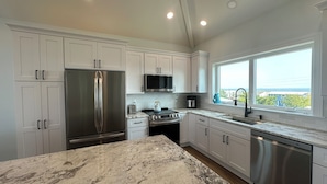 A modern kitchen with white cabinets, stainless steel appliances, and a marble countertop.