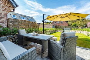 An outdoor patio with wicker furniture, a table, and a yellow umbrella.