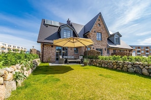 A large brick house with a stone wall and a patio area with a table and chairs.
