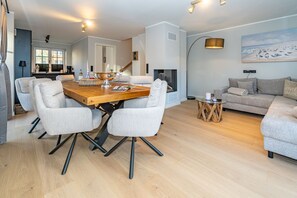 Un salon moderne avec une table à manger en bois, des chaises grises à revêtement, un canapé gris et une table basse ronde.