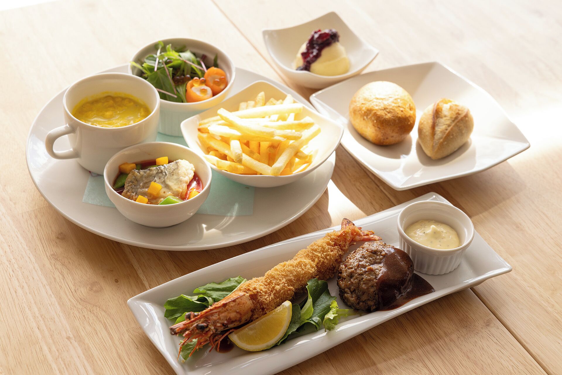 A variety of dishes including seafood, fries, and bread, served on white plates and bowls.