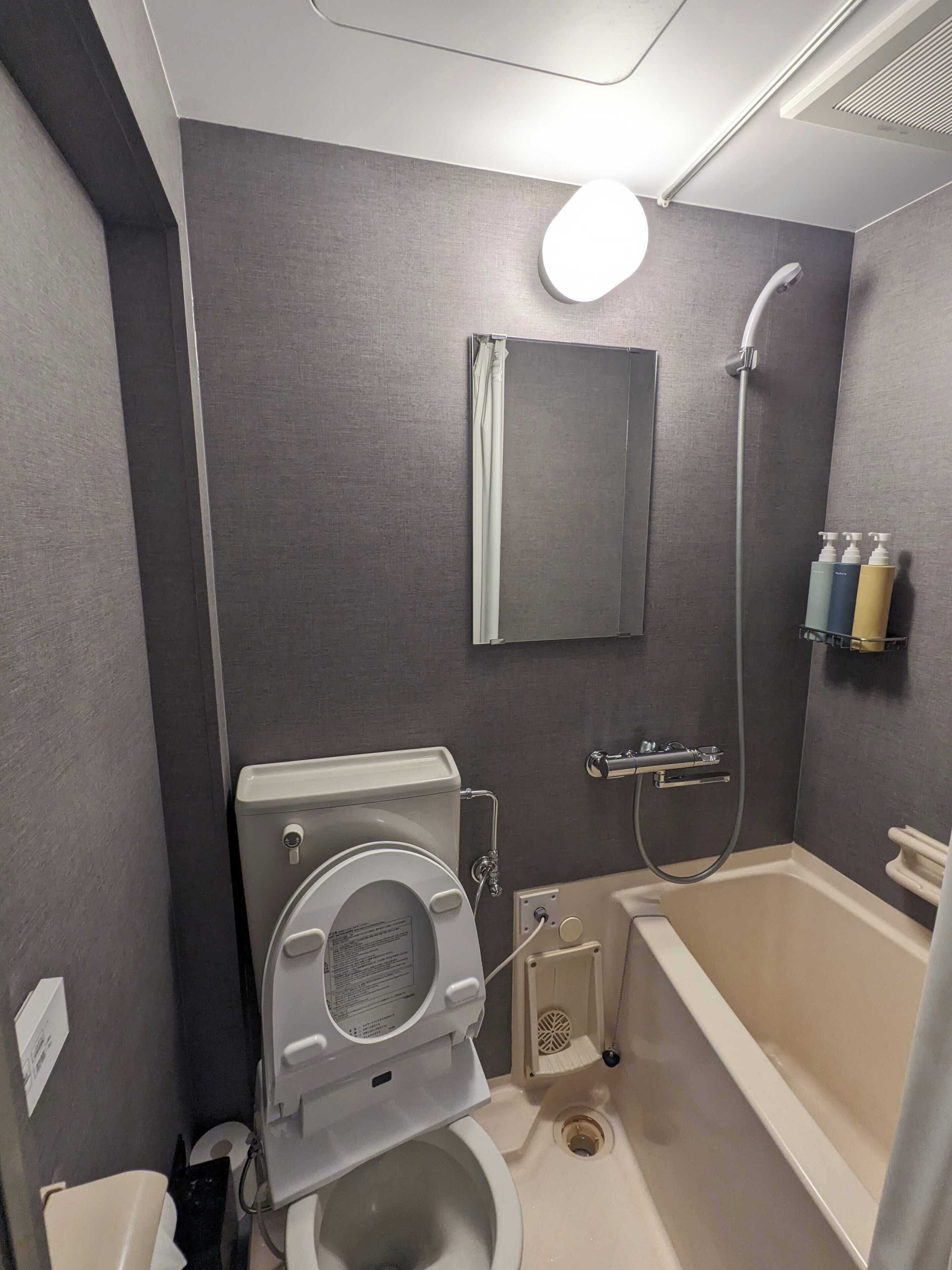 A compact bathroom with a toilet, bidet, and bathtub.
