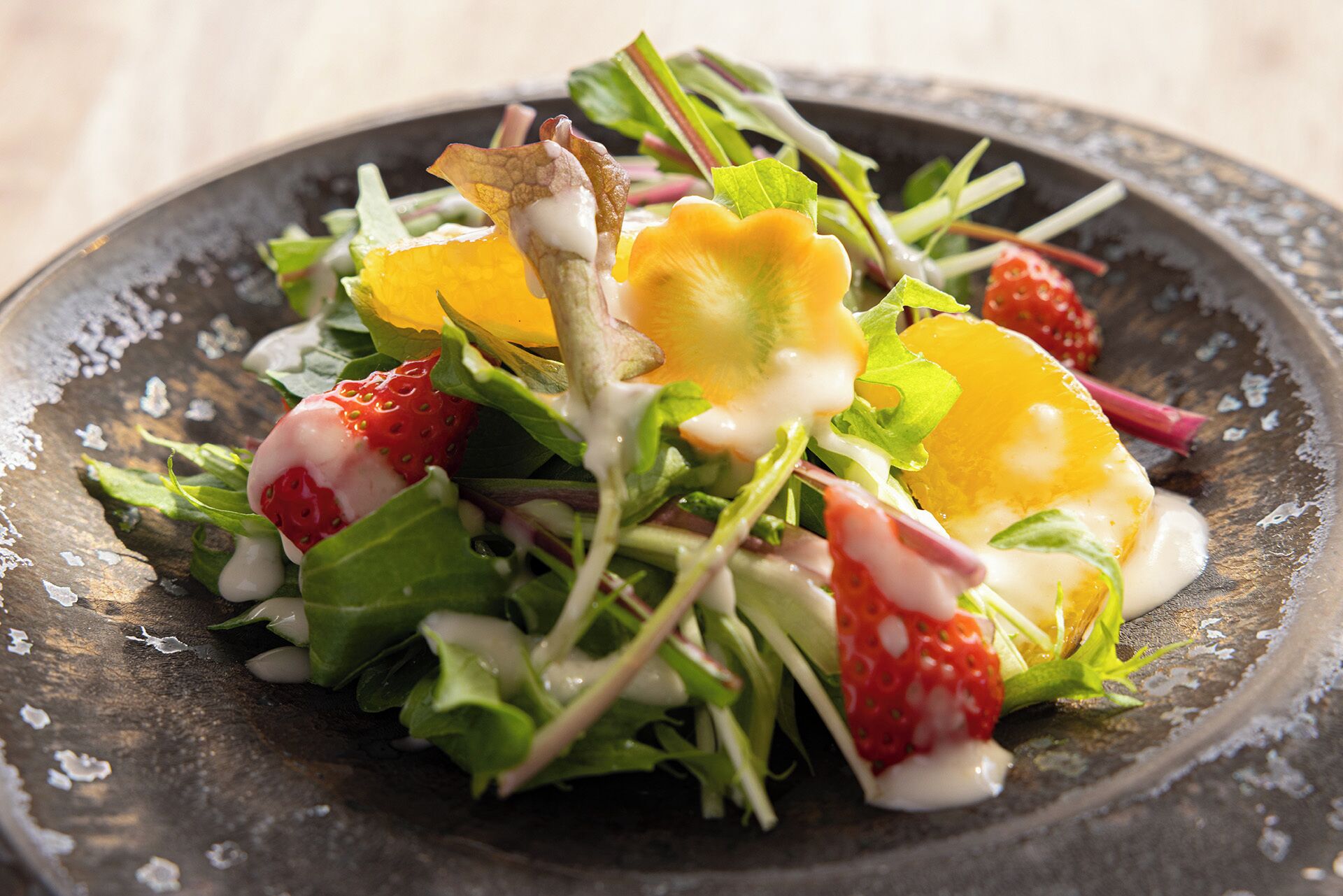 Une salade composée de divers légumes et fruits, présentée dans une assiette.