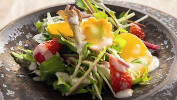 Une salade composée de divers légumes et fruits, présentée dans une assiette.