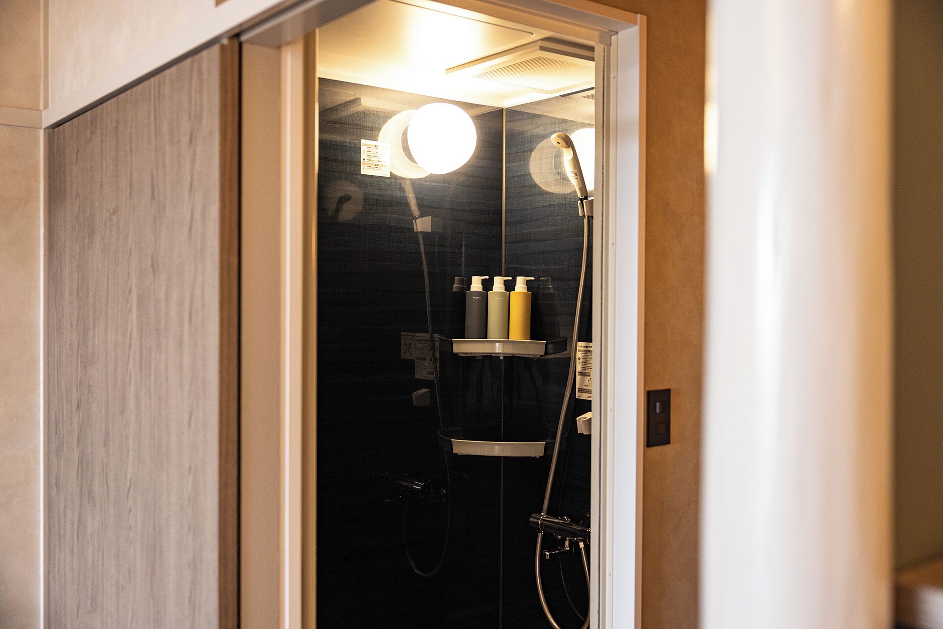 A modern shower with a glass enclosure, a handheld showerhead, and a wall-mounted faucet.