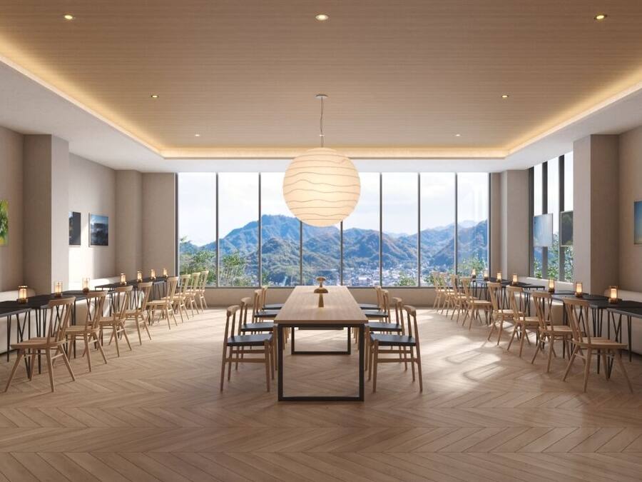 A spacious conference room with a large table and chairs, large windows with a mountain view, and a modern ceiling design.