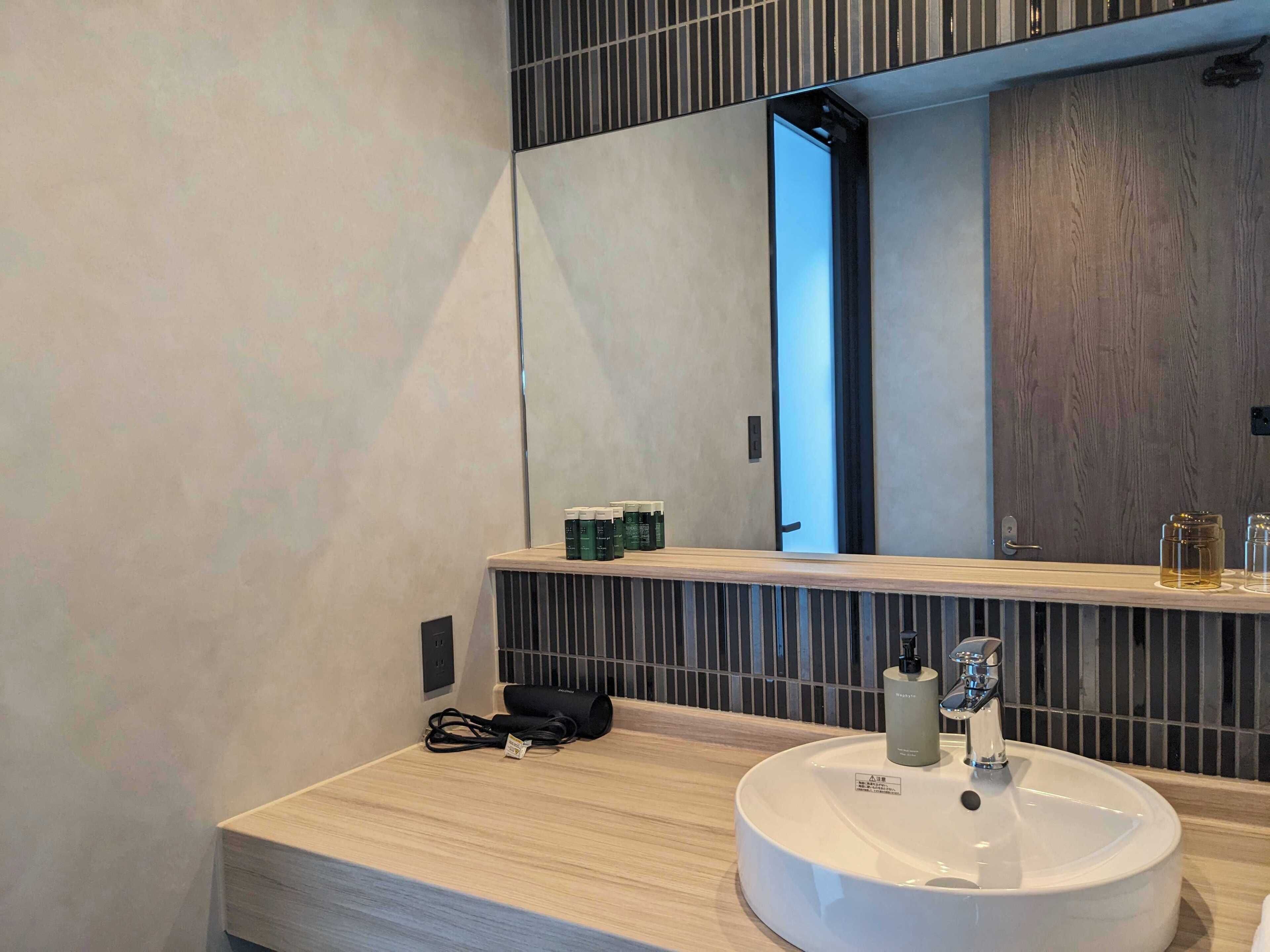 Une salle de bain moderne avec un grand miroir, un lavabo et des articles de toilette disposés sur le comptoir.