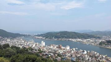 A coastal cityscape with dense urban development, a river, and hills in the background.