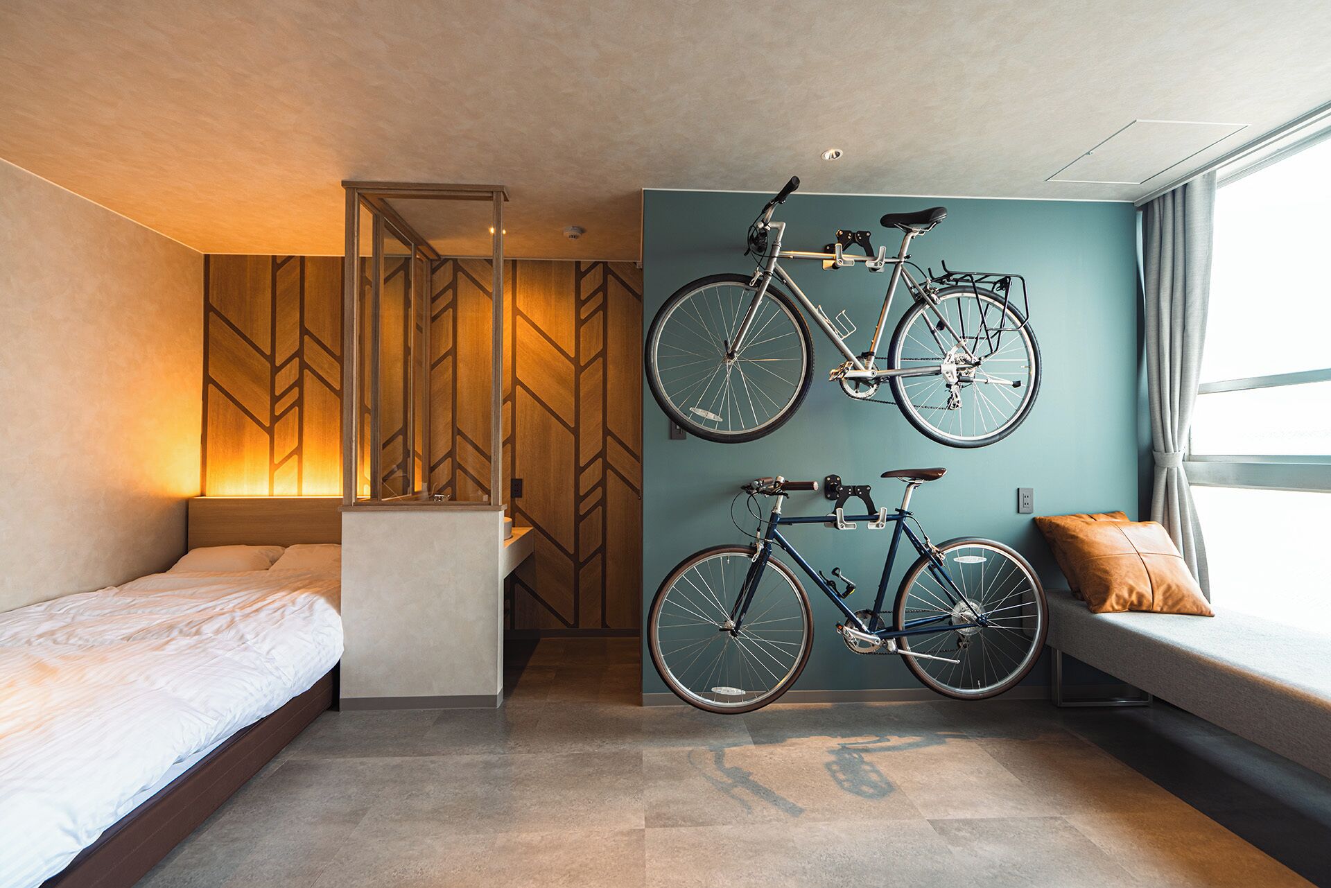 Ett modernt hotellrum med en säng, en soffa och två cyklar som hänger på väggen.
