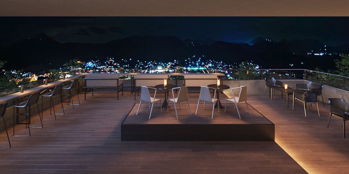 Una terrazza sul tetto con tavoli e sedie, affacciata su un panorama cittadino di notte.