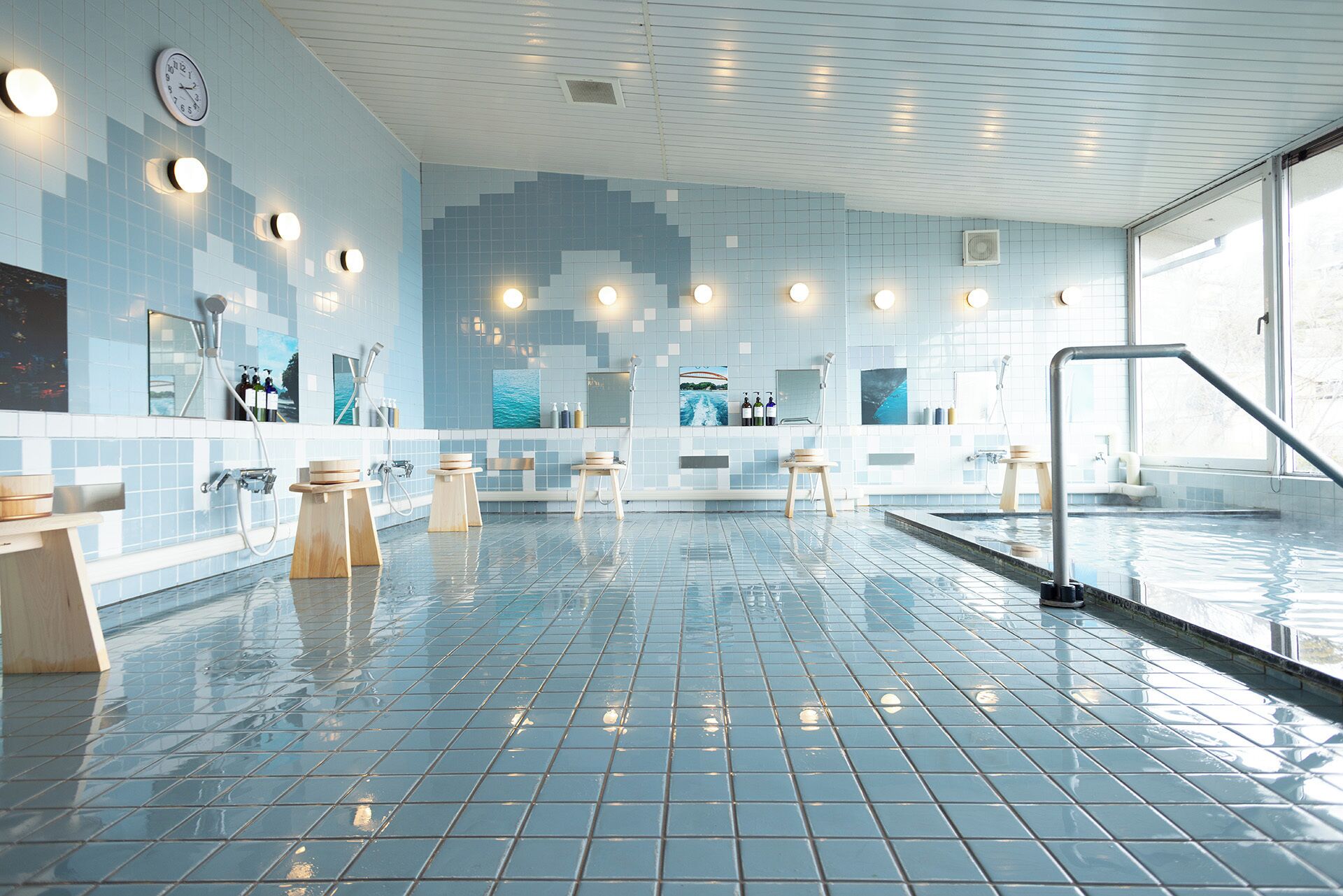 A modern indoor swimming pool with tiled walls, multiple showerheads, and a clear view of the pool area.