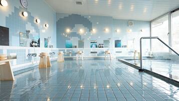 A modern indoor swimming pool with tiled walls, multiple showerheads, and a clear view of the pool area.