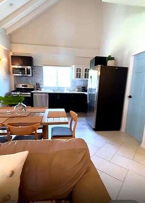 A compact kitchen with modern appliances, a dining area with a table and chairs, and a visible door leading to another room. - COUVA Home with a POOL,  near Holy Faith Convent!! (Couva)
