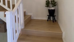 Una escalera con barandillas blancas, una lámpara de pared y una planta en maceta.
