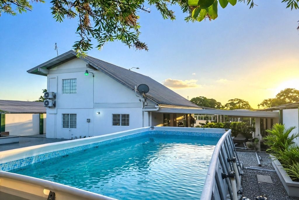 A swimming pool adjacent to a building with a flat roof and satellite dish.