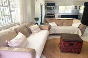 Una sala moderna con un conjunto de sofás, una mesa de comedor y una cocina al fondo.